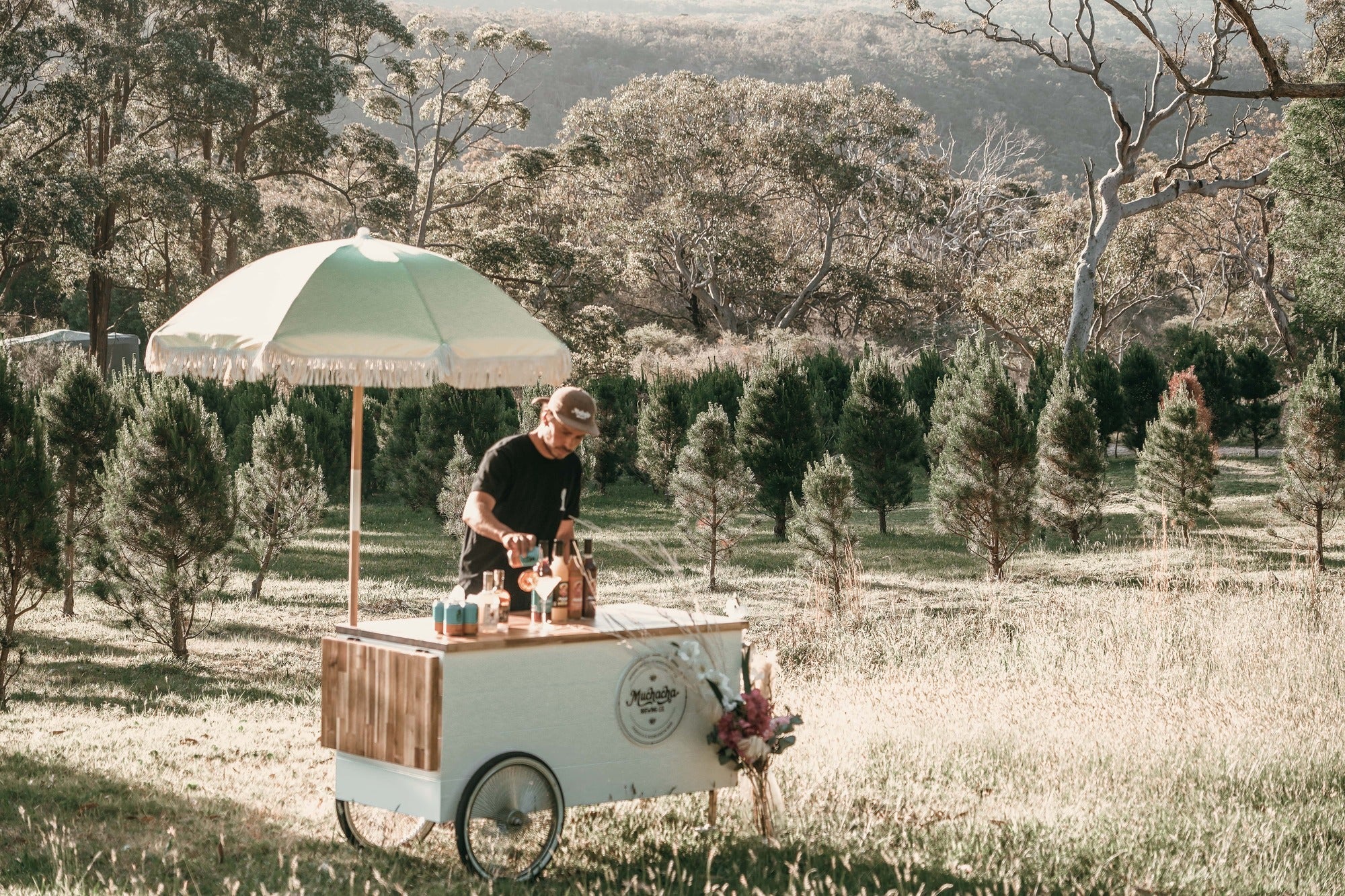 Person working at a mobile cocktail cart for weddings with an  in a scenic outdoor setting