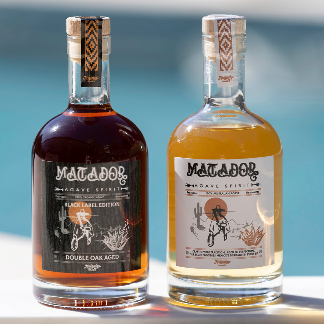 Two bottles of Matador Agave Spirits with different labels on a blurred background