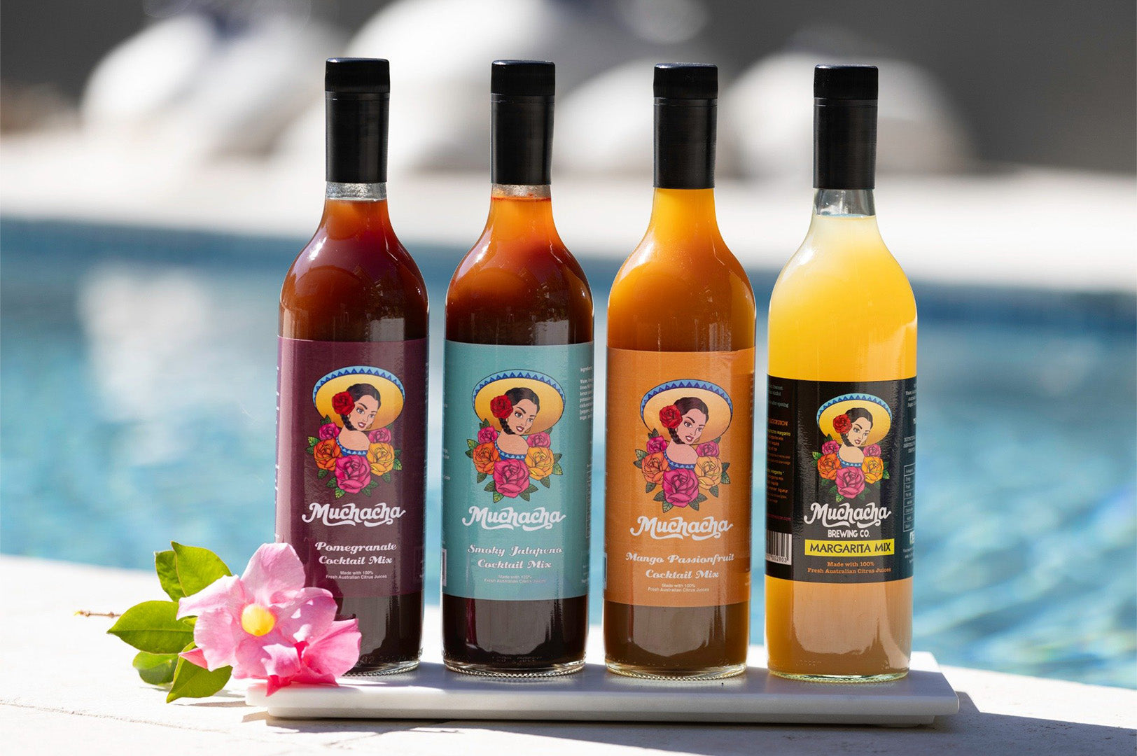 Four bottles of cocktail brand drinks on a tray with a blurred pool background